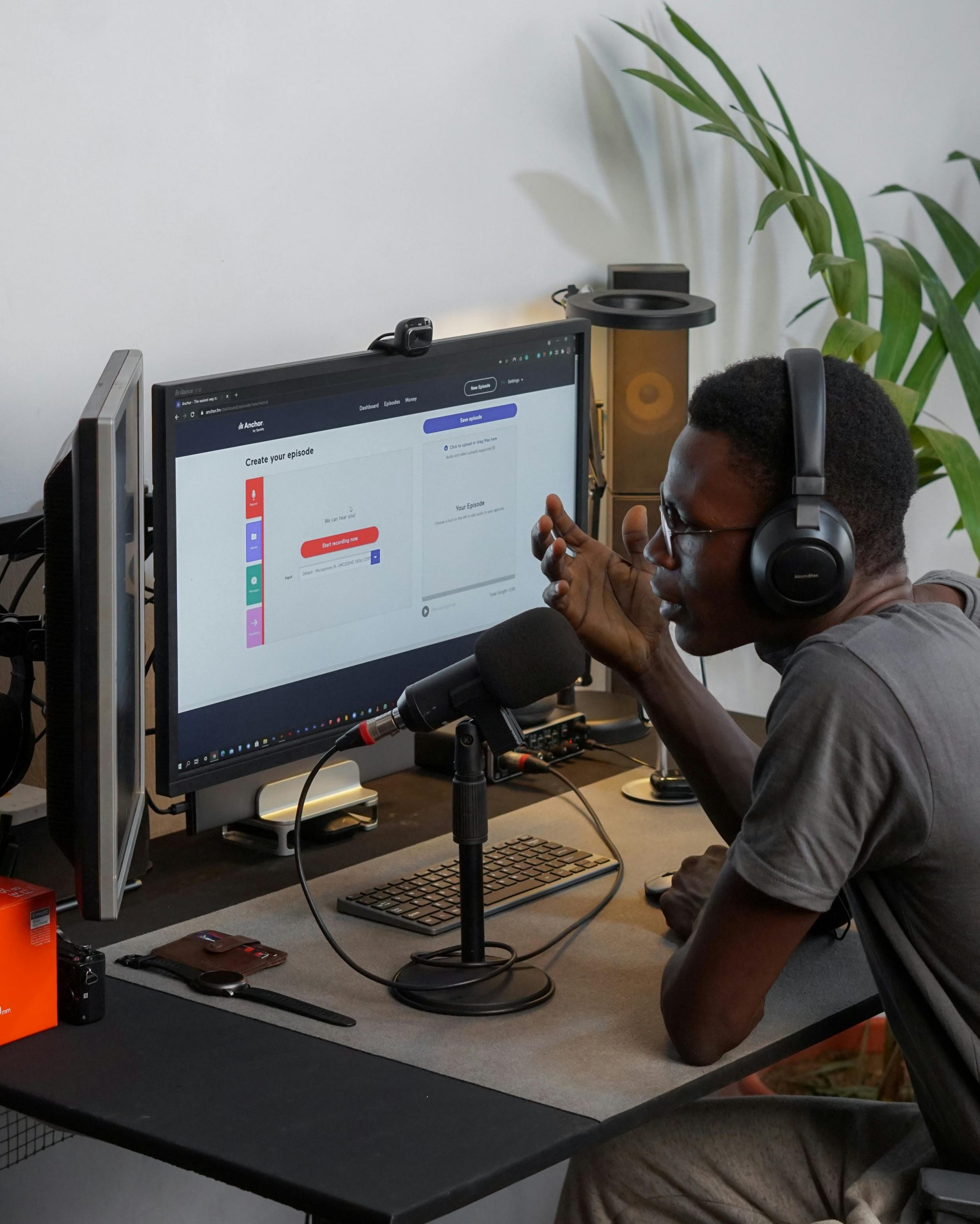 Man using headphones and microphone in home studio, engaging in podcast recording.
